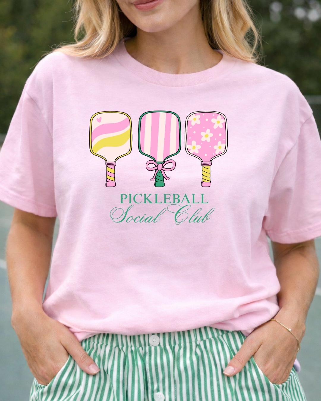Person wearing a pink t-shirt with pickleball-themed design and text.