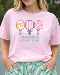 Person wearing a pink t-shirt with pickleball-themed design and text.