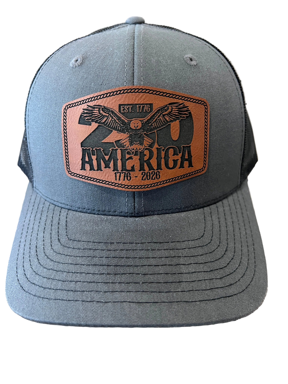 Gray cap with a leather patch featuring an eagle and 'America' text on a wooden surface
